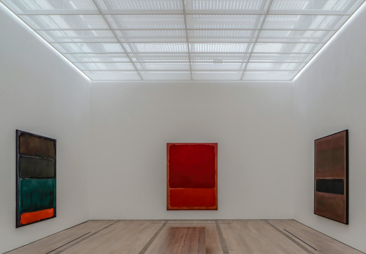 Tre dipinti astratti esposti su pareti bianche di una galleria.